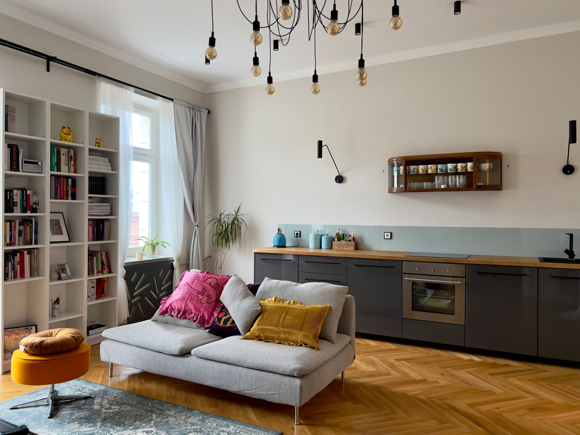 Salon z aneksem kuchennym i wiszącymi lampami z żarówkami